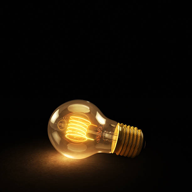 istock Glowing Incandescent Light Bulb on a Dark Background 504365057