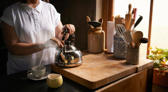 Cropped shot of a woman making a cup of tea in her kitchen