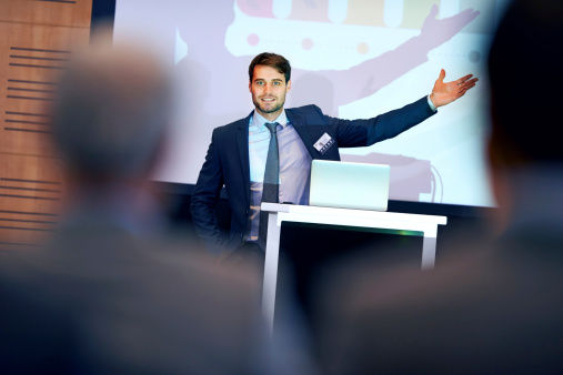 A confident businessman gesturing while giving a presentation at a press conference