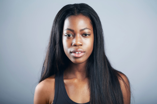 Portrait of an attractive young woman in casual wear standing against a gray background