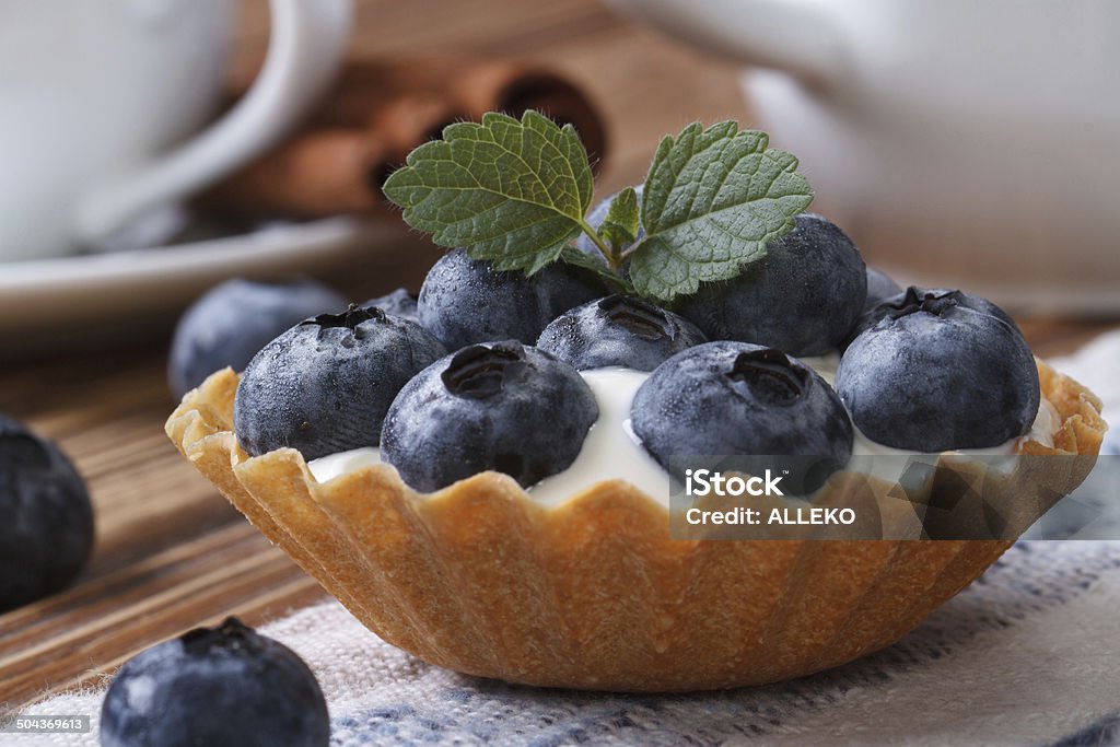 Tartlets with blueberries and cream closeup horizontal Tartlets with blueberries and cream closeup on wooden table horizontal Backgrounds Stock Photo
