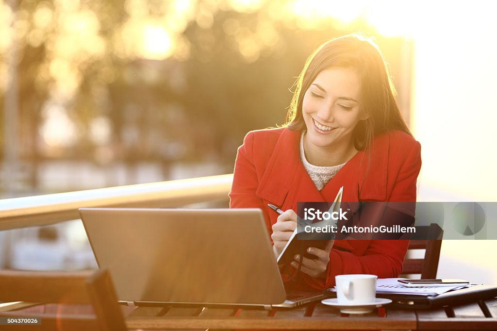 Feelancer working with laptop in winter Feelancer working with laptop in winter taking notes in an agenda outdoors Computer Stock Photo