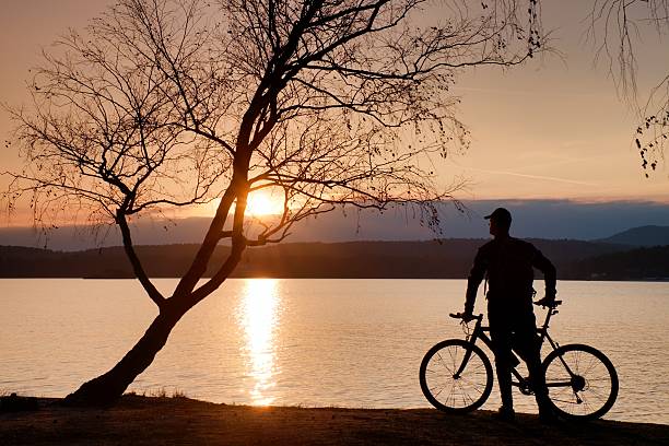 istock Young man cyclist silhouette on pink orange sky 504370520