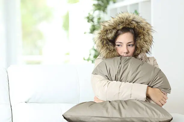 Angry woman warmly clothed in a cold home sitting on a couch