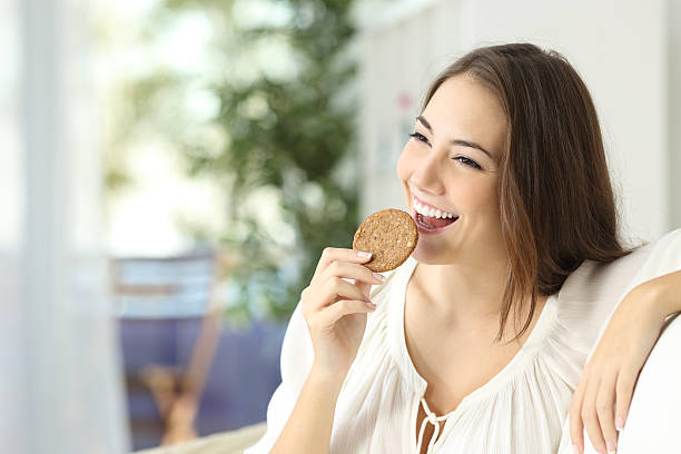 ragazza felice mangia un dietetic cookie - bite sized foto e immagini stock