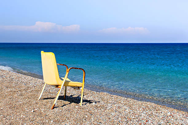 A broken and old chair at the greek beach. The concept of financial crisis