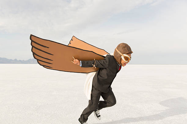 junge business mann läuft mit karton wings - taking off business creativity adventure stock-fotos und bilder