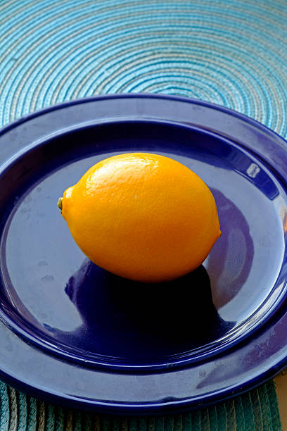 istock Single fresh lemon on a blue plate portrait 504374214