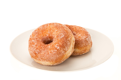 Two sugar coated donuts on a plate - studio shot with a white background