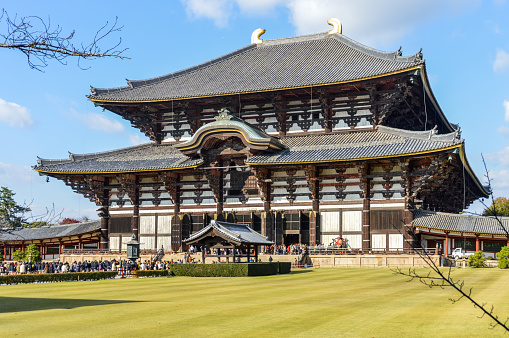 Nara, Japan - November 28, 2015: Todaiji is one of Japan's most famous and historically significant temples and a landmark of Nara. The temple was constructed in 752 as the head temple of all provincial Buddhist temples of Japan and grew so powerful that the capital was moved from Nara to Nagaoka in 784 in order to lower the temple's influence on government affairs. Todaiji's main hall, the Daibutsuden (Big Buddha Hall) is the world's largest wooden building, despite the fact that the present reconstruction of 1692 is only two thirds of the original temple hall's size. The massive building houses one of Japan's largest bronze statues of Buddha (Daibutsu). The 15 meters tall, seated Buddha represents Vairocana and is flanked by two Bodhisattvas. 