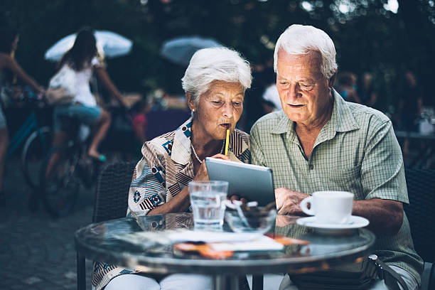 Senior couple at cafe in the evening using digital tablet