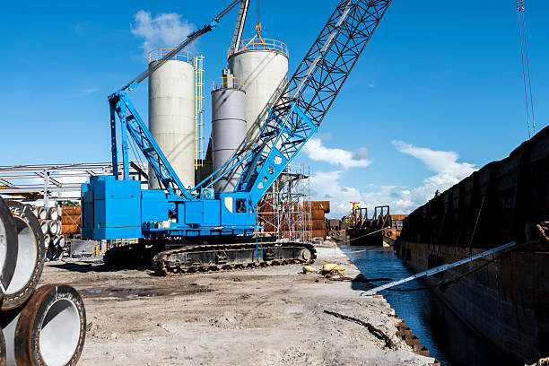 Lifting Crane Crane on tracks on the bank prepares to unload barges.  jib stock pictures, royalty-free photos & images