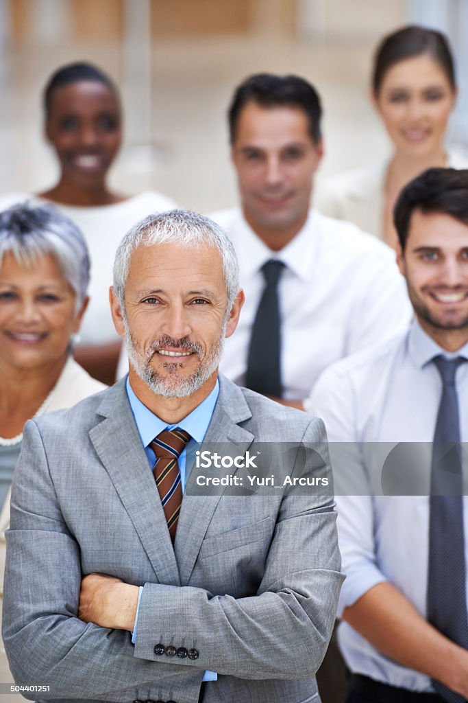 We turn possibilities into realities Portrait of a smiling businessman surrounded by a group of his colleagues Corporate Business Stock Photo