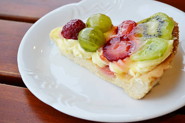 istock Slice of fruit cake with cream on a white plate 504401641