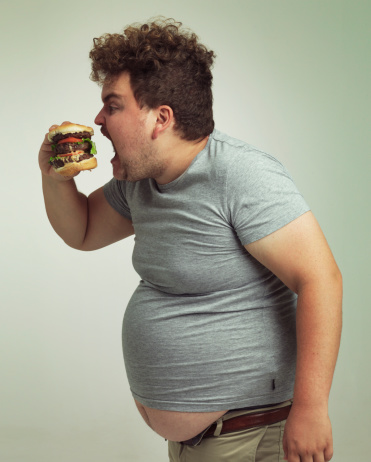 Studio shot of an overweight man biting into a burger