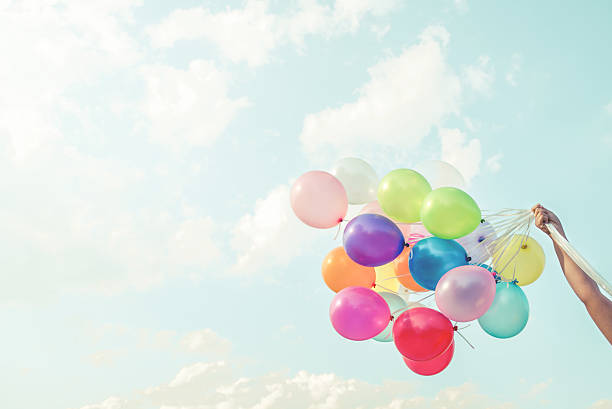 girl mano agarrando multicoloured globos - spaciousness fotografías e imágenes de stock