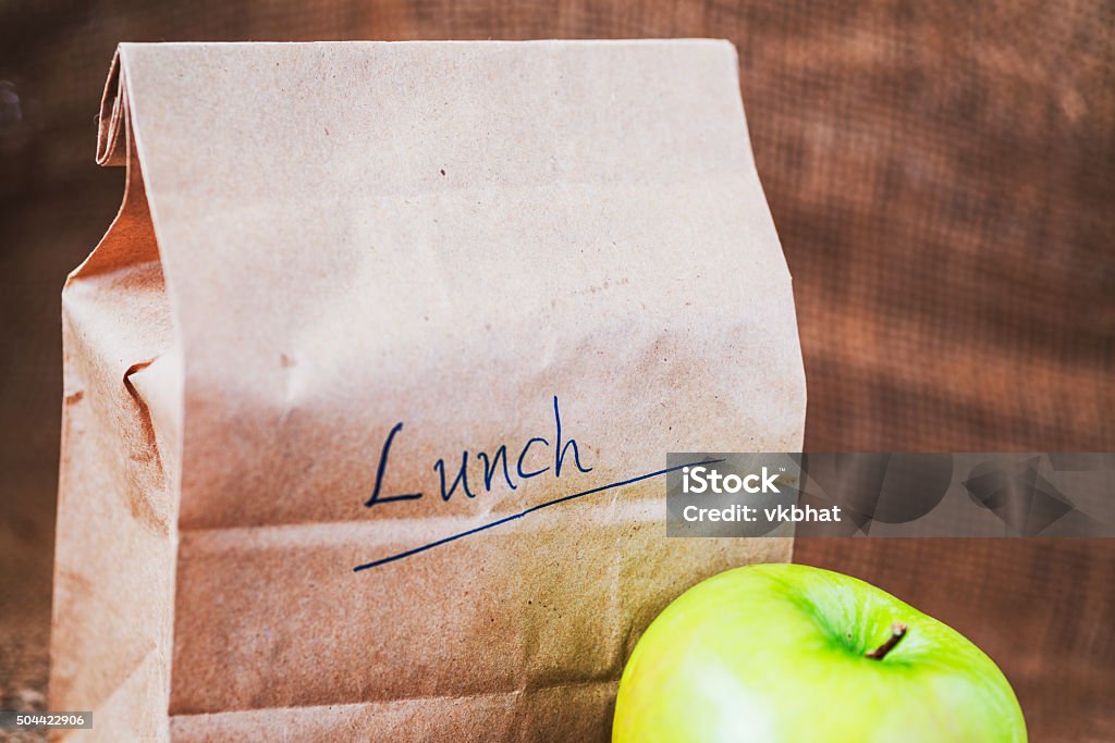 Brown bag lunch with apple Brown bag lunch and green apple on canvas background and copy space Packed Lunch Stock Photo