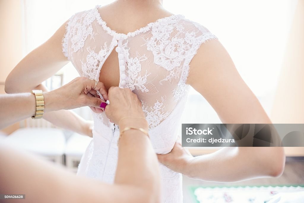 Putting on wedding dress Mother helping the bride - her daughter to put her wedding dress on, close up photo Bride Stock Photo