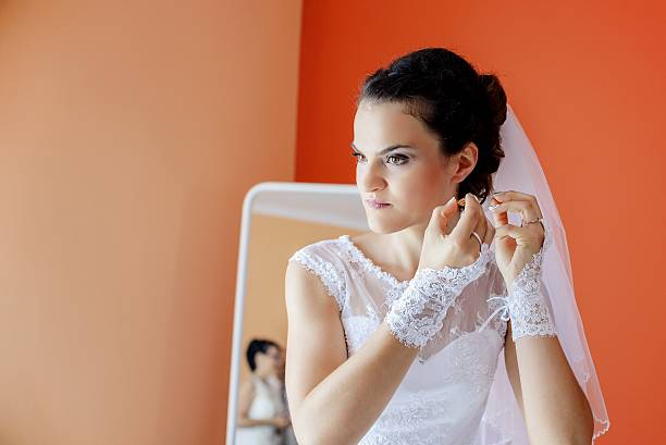 istock Beautiful bride in white wedding dress puts on earring. 504426738