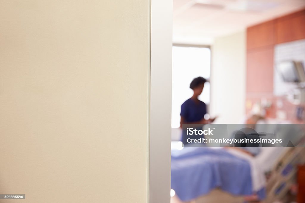 Focus On Hospital Room Sign With Nurse Talking To Patient Door Stock Photo