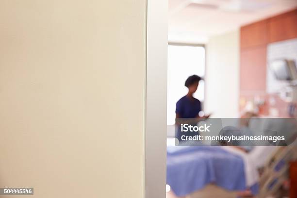 Focus On Hospital Room Sign With Nurse Talking To Patient Stock Photo - Download Image Now