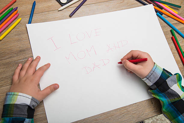 istock boy writes a message to Mother and Father 504446202