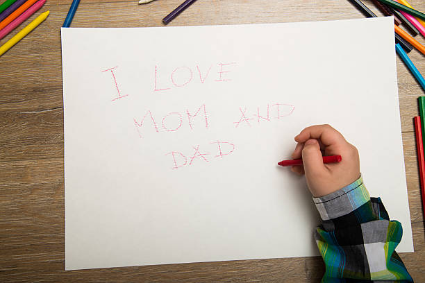 istock boy writes a message to Mother and Father 504446358