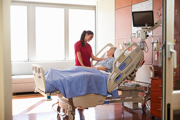 enfermera hablando con un paciente senior mujer en la cama de hospital - patient room fotografías e imágenes de stock