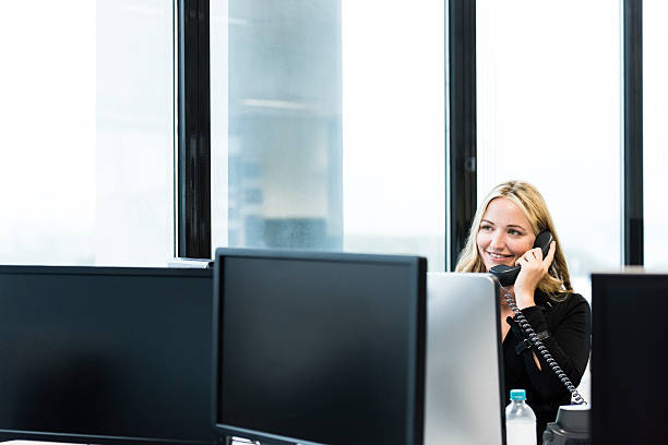 istock Businesswoman on phone at desk with computer monitors 504448706
