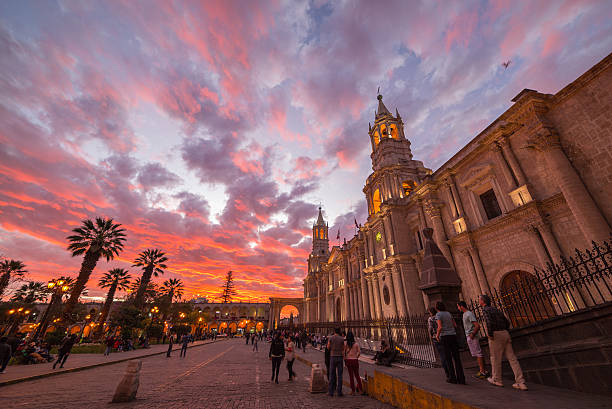 Cathedral of Arequipa, Peru, with stunning sky at dusk Arequipa, Peru - August 16, 2015: People roaming in Plaza de Armas in front of the Cathedral of Arequipa at dusk. Wide angle view from below with scenic colorful sky and clouds. arequipa province stock pictures, royalty-free photos & images