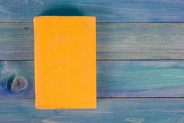 istock Yellow book on blue wooden background 504450504