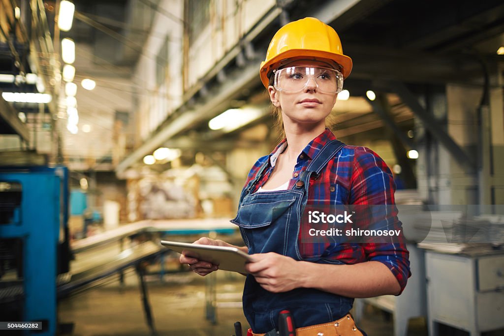 Factory female worker Young factory worker controlling the work Protective Eyewear Stock Photo