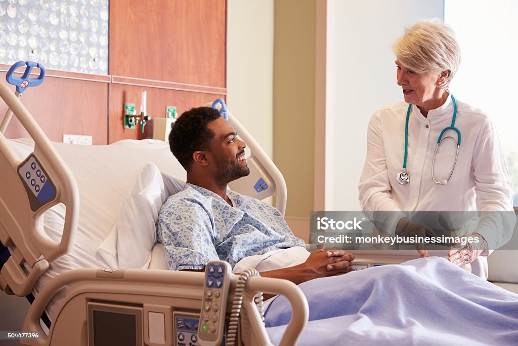 Female Doctor Talking To Male Patient In Hospital Bed 30-39 Years Stock Photo