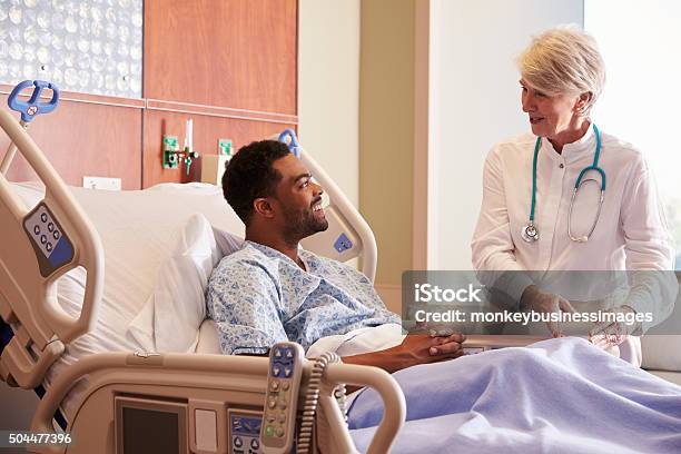 Female Doctor Talking To Male Patient In Hospital Bed Stock Photo - Download Image Now