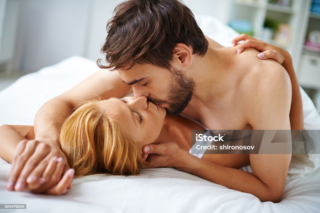 Couple kissing Hands of female and male lying on bed and kissing Sex and Reproduction Stock Photo