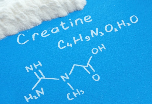 Сreatine powder with  chemical formula of creatine on a blue paper