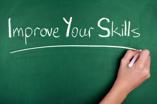 Woman hand writing 'Improve Your Skills' on green blackboard