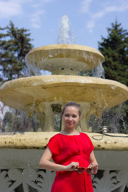 pregnant woman is the fourth month A pregnant woman is the fourth month in a red dress for a walk in Gorky Park, Moscow 3 months pregnant belly stock pictures, royalty-free photos & images