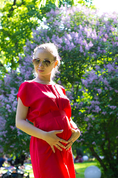 pregnant woman is the fourth month A pregnant woman is the fourth month in a red dress for a walk in Gorky Park, Moscow 3 months pregnant belly stock pictures, royalty-free photos & images