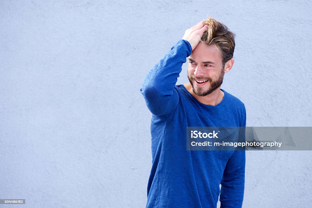 Male fashion model smiling with hand in hair Portrait of a male fashion model smiling with hand in hair Men Stock Photo