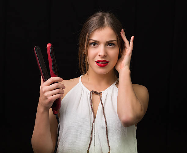 istock Woman with a flat hair iron 504487362