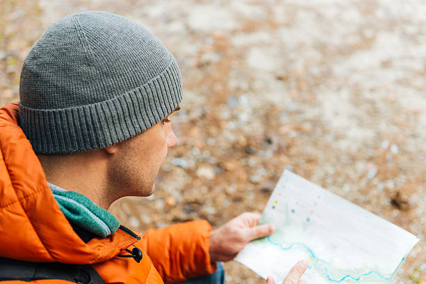 istock Man hiking in woods in winter and looking at map 504487472