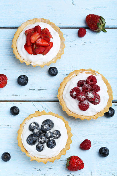 istock Dessert tartlets with berries on blue wooden background 504489324