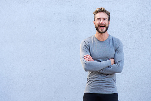 Portrait of a male fitness trainer laughing with arms crossed