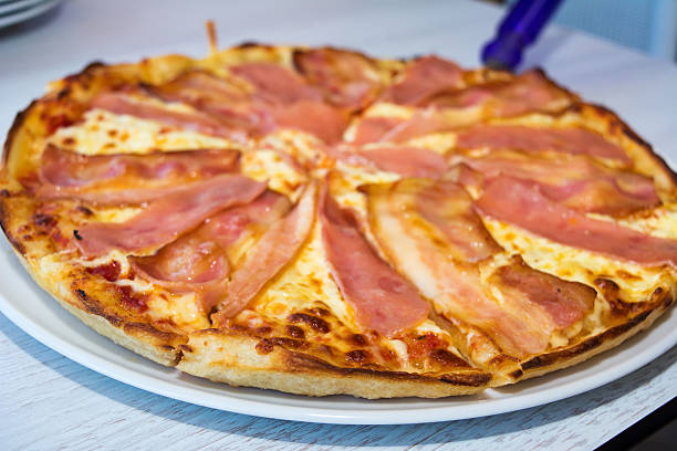 Sliced pizza with ham, bacon and four kind of a cheese