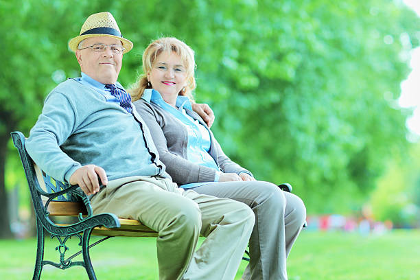 istock Mature couple posing in park seated on bench 504509315