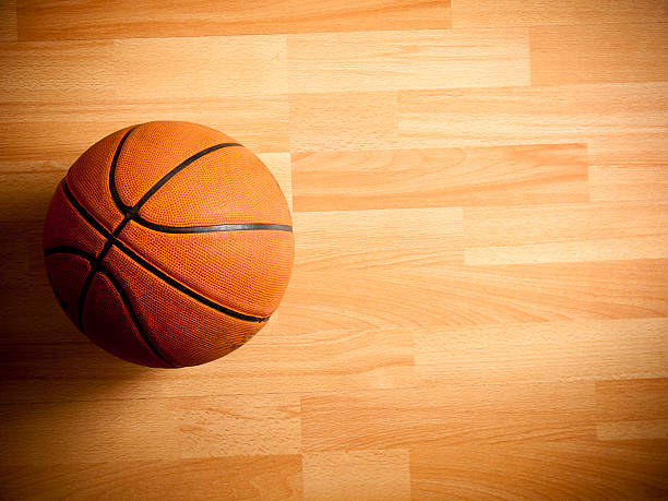 An official orange ball on a hardwood basketball court stock photo