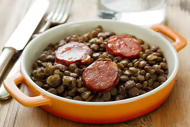 chorizo with lentil on dish and glass of water