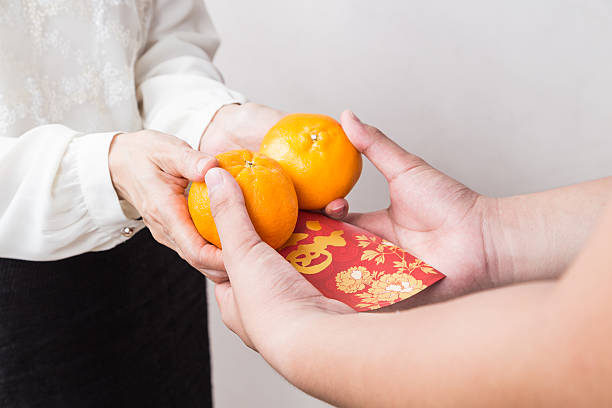 mujer dando mandarín naranjas, rojo cubren con buena suerte de caracteres - currency envelope luck new fotografías e imágenes de stock