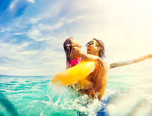 pai e filha saltar e divertir-se juntas no mar - summer swimming beach vacations imagens e fotografias de stock